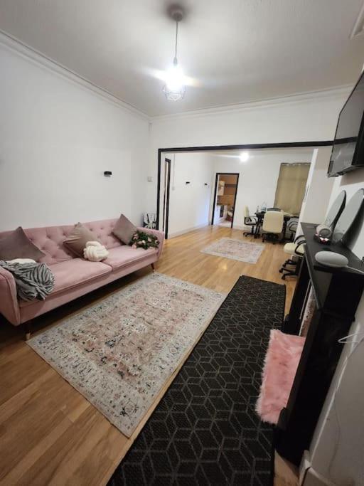 sala de estar con sofá rosa y alfombra en Luton Airport - Affordable Home, en Luton