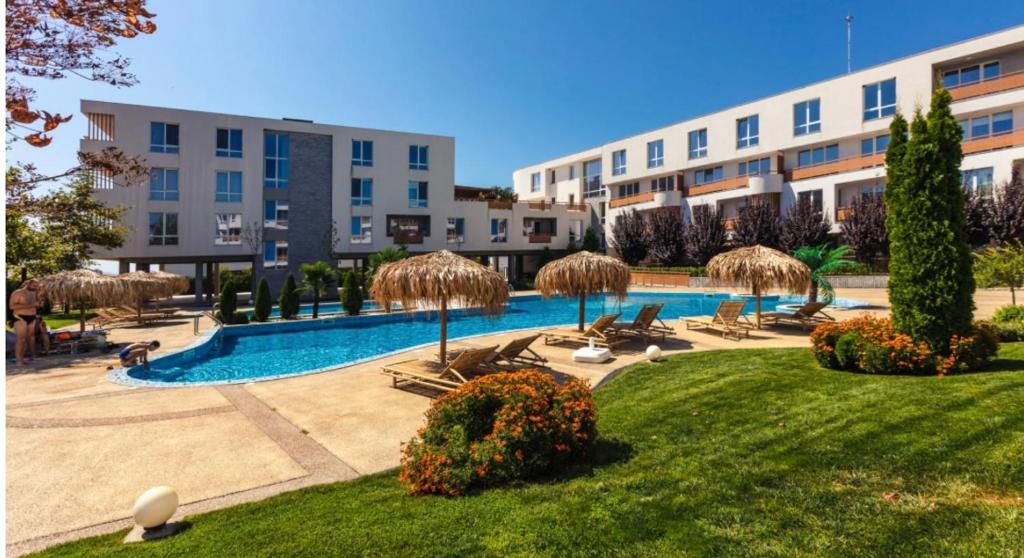 um resort com uma piscina com cadeiras e guarda-sóis em Апартамент за гости Incanto del mare em Sarafovo