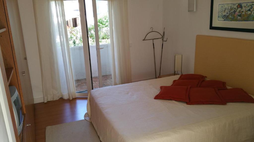 Un dormitorio con una cama con almohadas rojas. en Villapinheiros, en Vilamoura