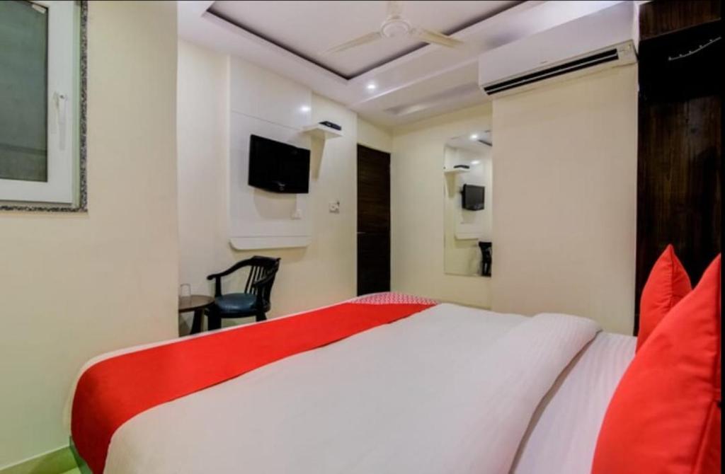 a bedroom with a large white bed with red pillows at Hotel India continental in New Delhi