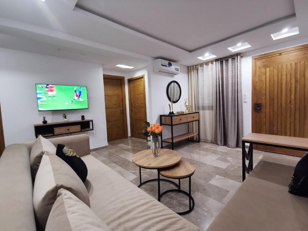 uma sala de estar com um sofá e uma televisão em Appartement RDC pieds dans l'eau parking privée em Hammam Sousse