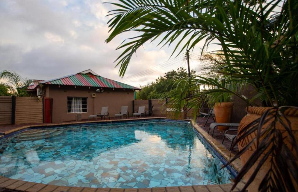 uma piscina com água azul em frente a uma casa em Happy Holiday Backpackers em Victoria Falls