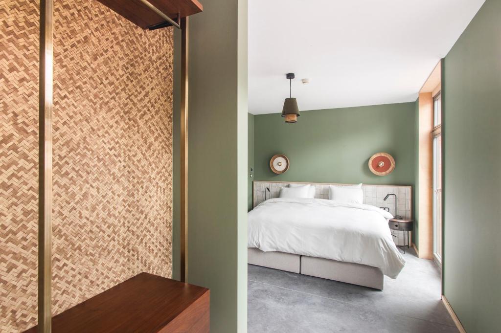 una camera con un letto bianco e una parete verde di L'olivier a Mons