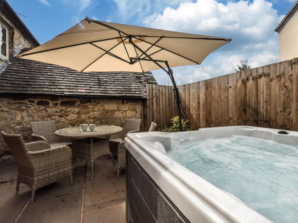 a hot tub with a table and an umbrella at 2 Bed in Brassington 77632 in Brassington