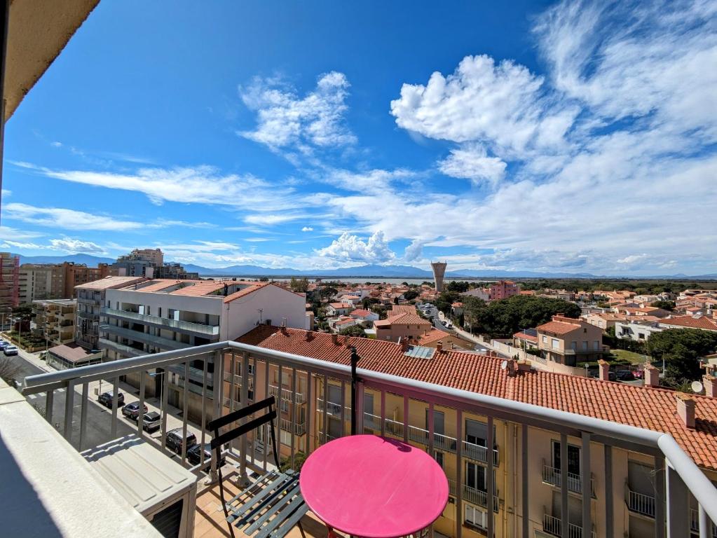 une vue d'une ville depuis un balcon avec un parapluie rose dans l'établissement Studio cosy en front de mer avec belle vue panoramique sur les montagnes, à Canet