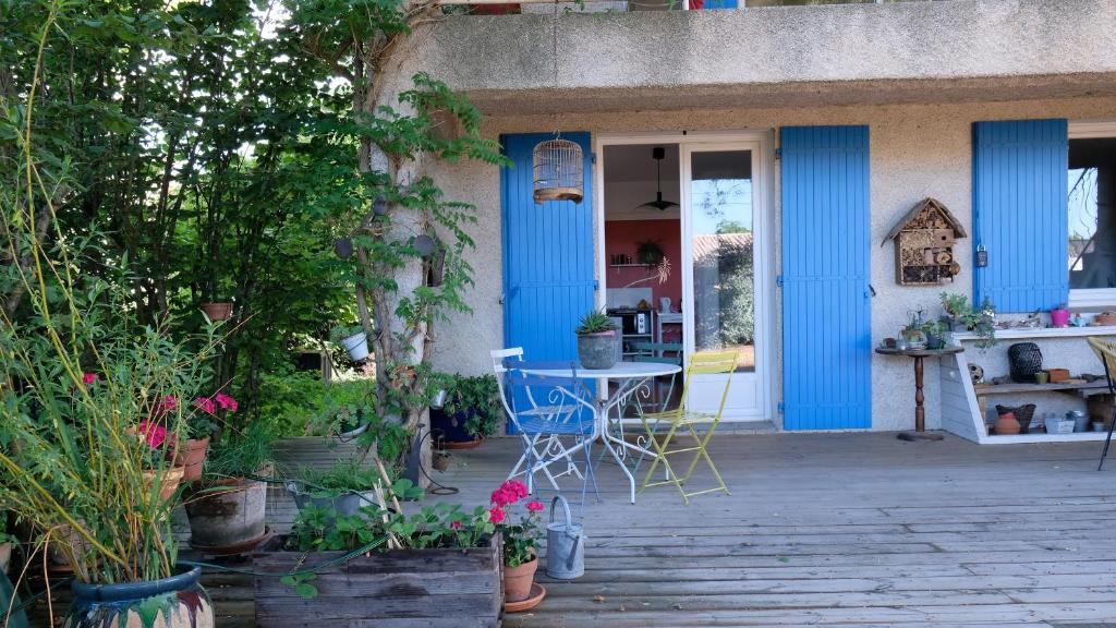 eine Veranda mit blauen Türen, einem Tisch und Pflanzen in der Unterkunft Appartement de plein pied Toulouse Nord in Castelginest