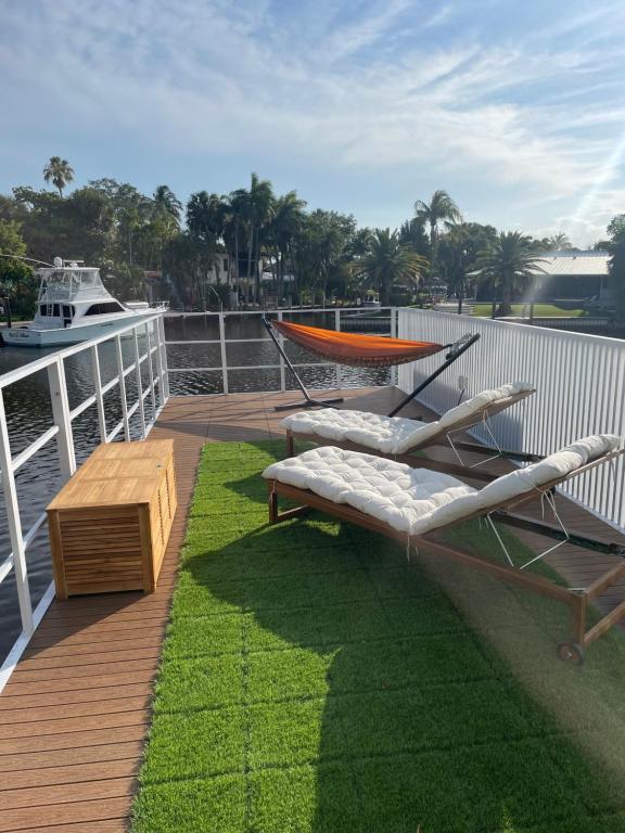 フォート・ローダーデールにあるUnique Houseboat Modern and Newのラウンジチェア2脚と芝生の上にテーブルが備わるデッキが付いています。