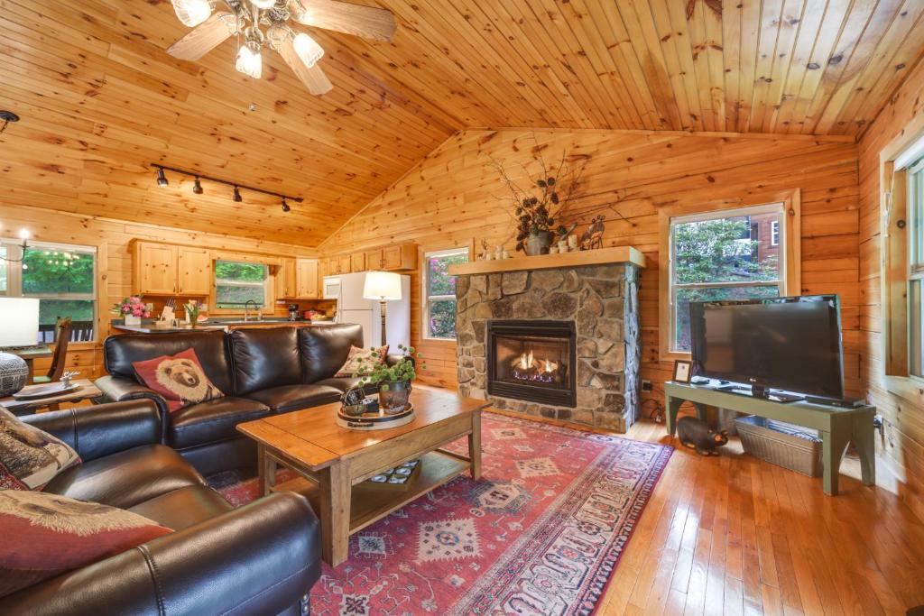 a living room with a couch and a fireplace at Peaceful Smoky Mountain Cabin with Deck and Fire Pit! in Waynesville