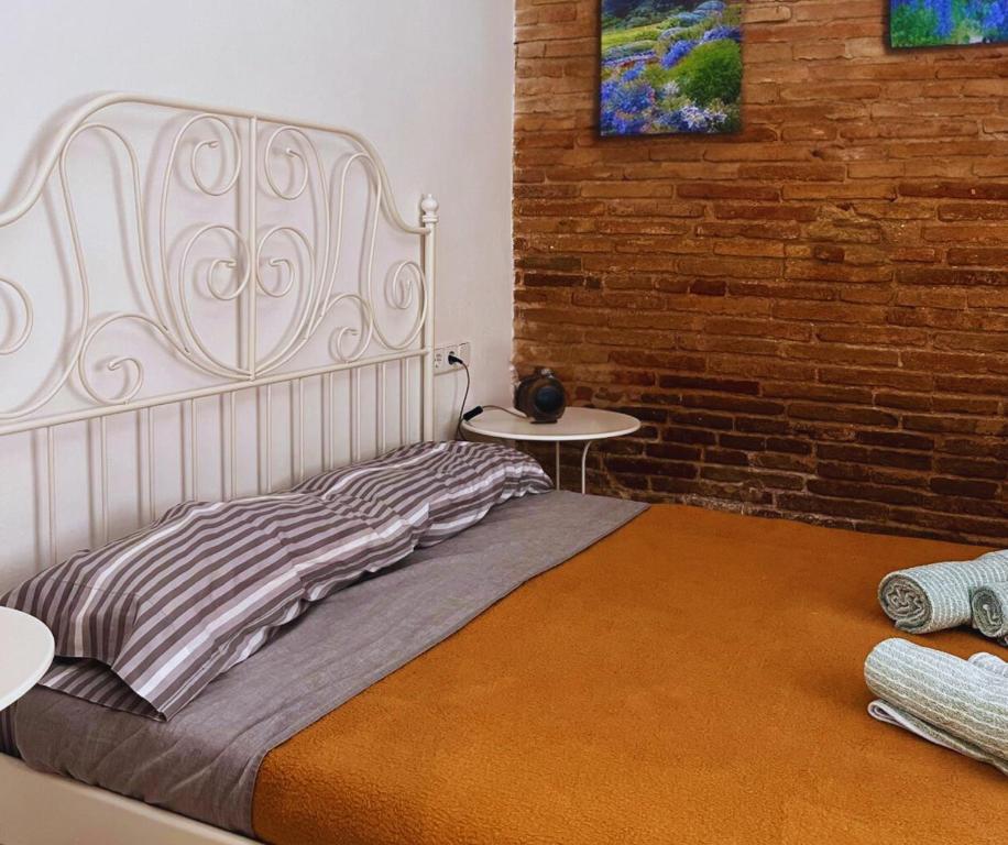 a bed in a room with a brick wall at SunFlower Apartment in Barcelona