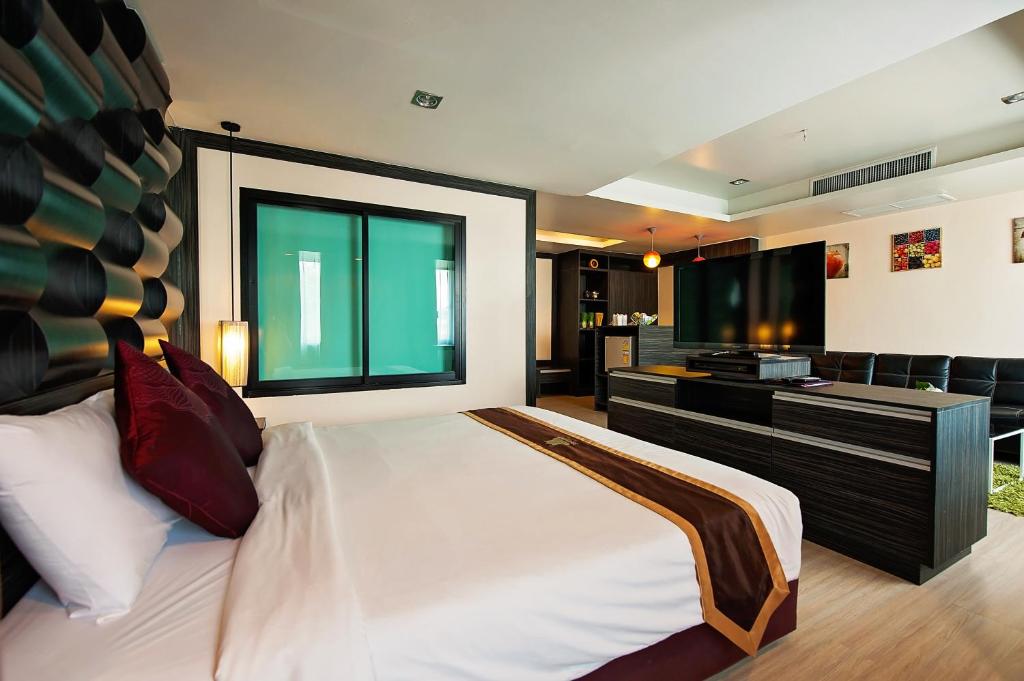 a bedroom with a large bed and a desk at Khon Kaen Hotel in Khon Kaen