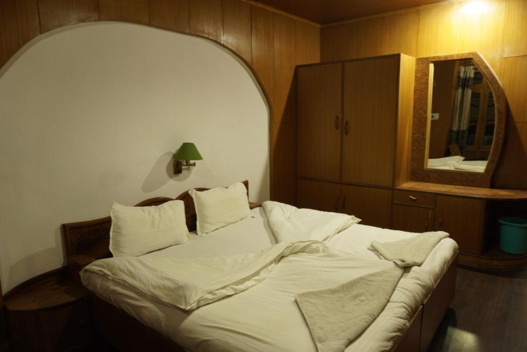 Schlafzimmer mit einem weißen Bett, einem Spiegel und einem Schrank in der Unterkunft Hotel Leh Castle in Leh