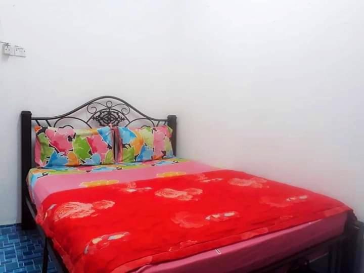 ein Bett mit einer roten Decke darüber in der Unterkunft RANIA HOMESTAY WAKAF CHE YEH in Kota Bharu