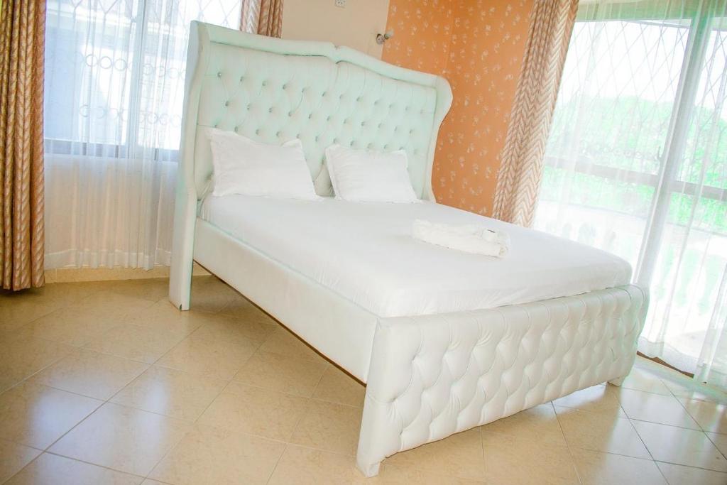 białe łóżko w pokoju z oknami w obiekcie Kerith Springs Family Holiday home Bamburi Msa w mieście Bamburi