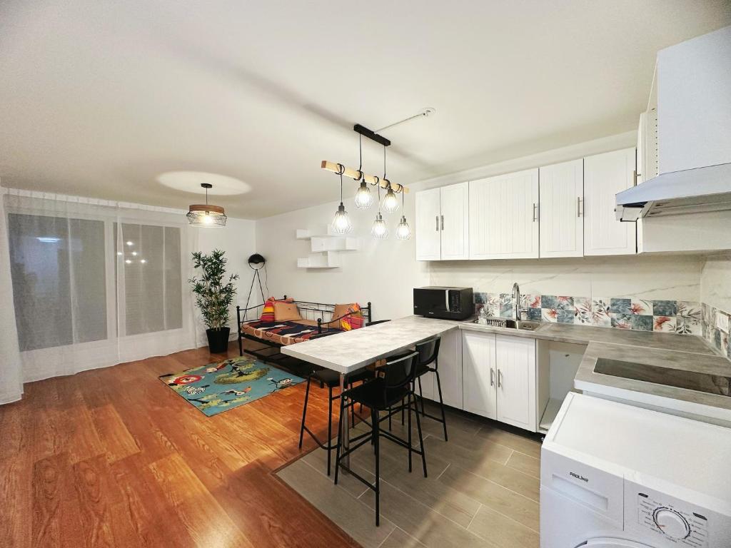 Una cocina con gabinetes blancos y una mesa con sillas. en W&L Paris Apartment 68m - 3 min Métro 4 - A Paris Centre 15min, en Bagneux