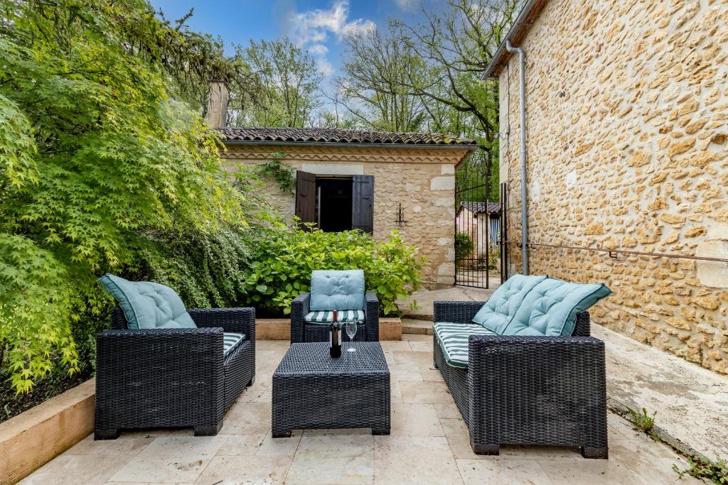 a patio with three wicker chairs and a table at Gîtes et chambres croix du sud in Saint-Amand-de-Vergt