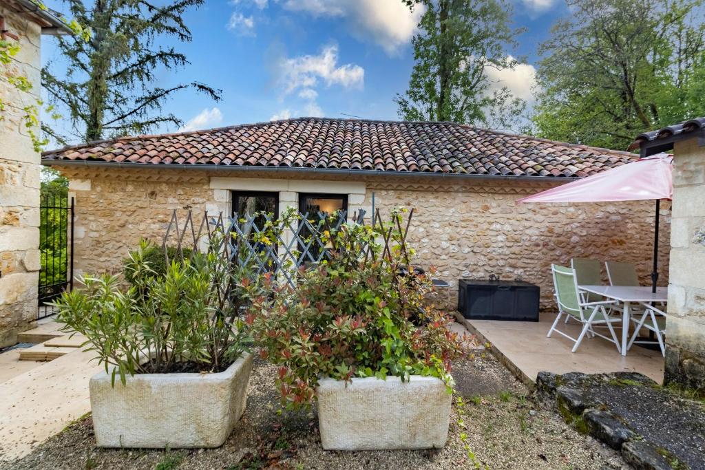 a small stone house with a patio and a table at Gîtes et chambres croix du sud in Saint-Amand-de-Vergt