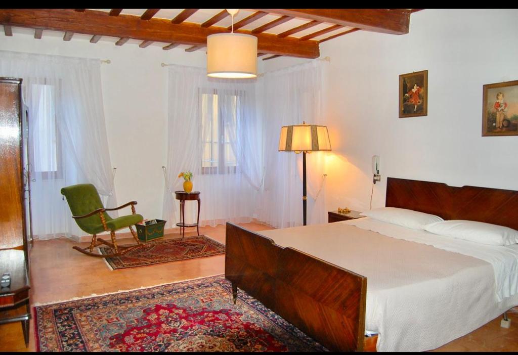 a bedroom with a large bed and a green chair at B&B Antica Dimora in Pergola