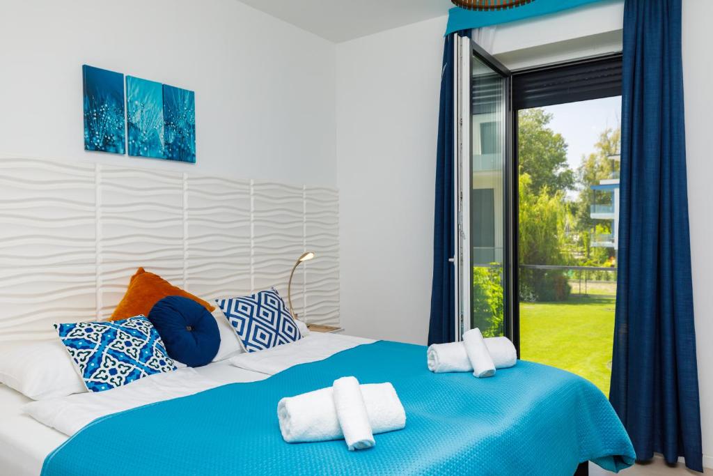 sypialnia z niebiesko-białym łóżkiem i oknem w obiekcie Blue4 Apartment w mieście Balatonfůzfő