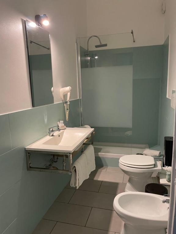 Un baño con lavabo, inodoro y espejo. en La Terrazza su Palermo, en Palermo