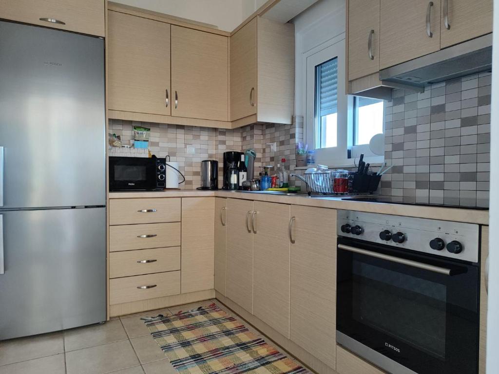 a kitchen with wooden cabinets and a stainless steel refrigerator at Sunrise guest house in Nydri