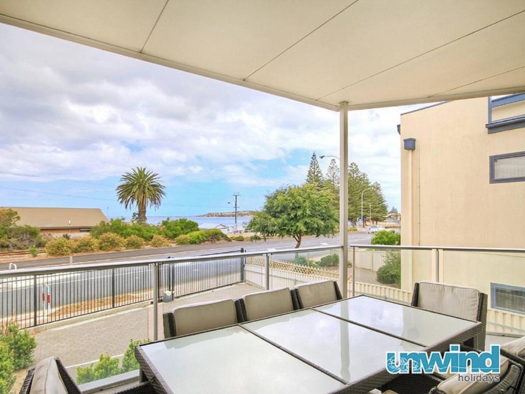 a balcony with a table and chairs and a view of a street at Block Escape - Ocean View Apartment No 1 in Victor Harbor