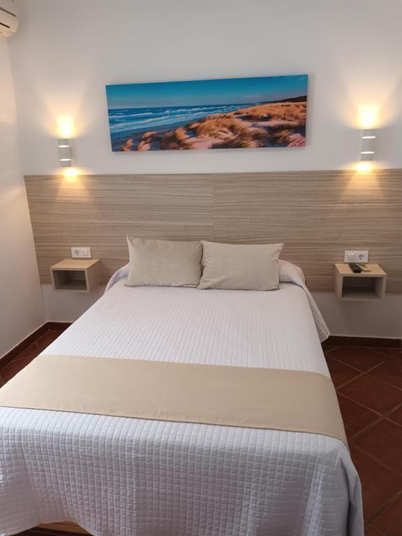 a bedroom with a large white bed with two night stands at Apartamentos Los Mellizos in Conil de la Frontera