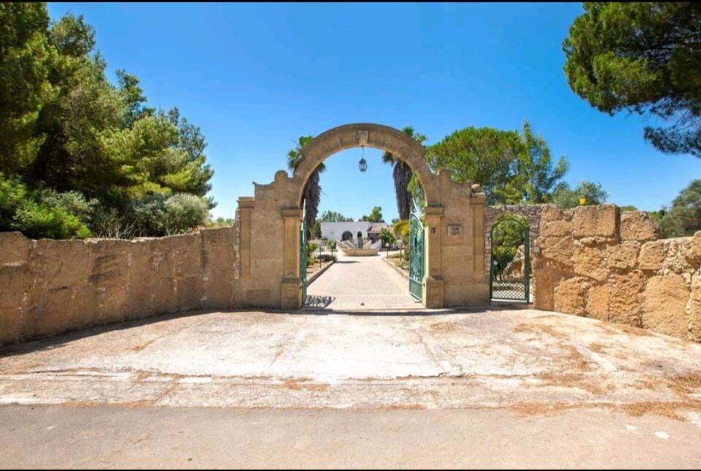 une arche dans une clôture en pierre avec une route dans l'établissement Villa Serenità Vintage Charm a Lido Marini, à Lido Marini