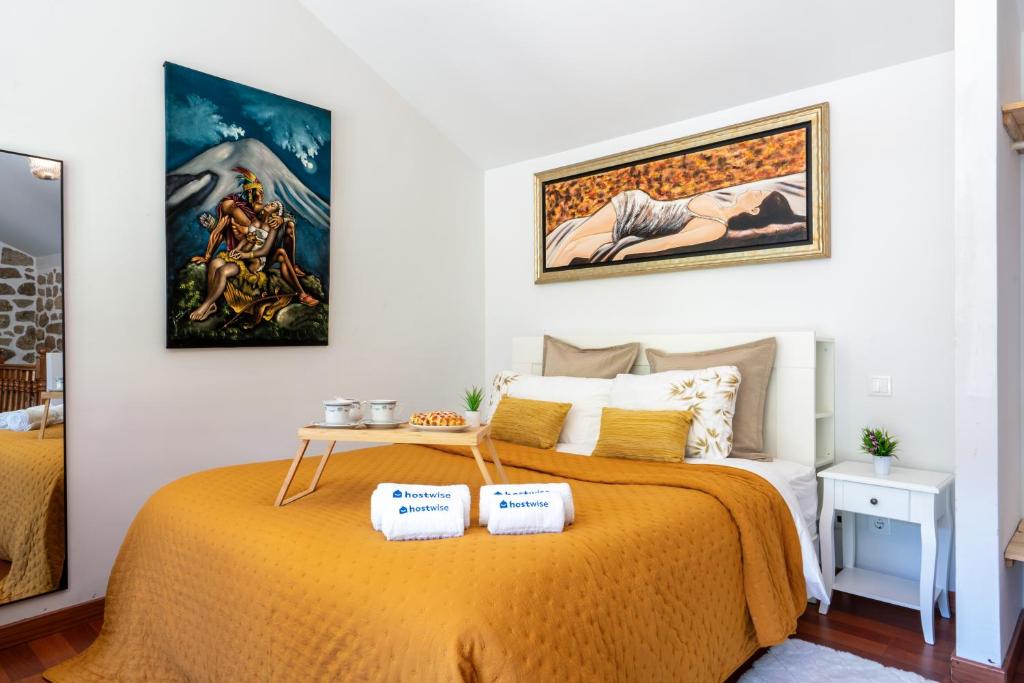 um quarto com uma cama com uma colcha laranja em Gerês Escape Retreat - Casa da Fonte de Pedra em Vieira do Minho
