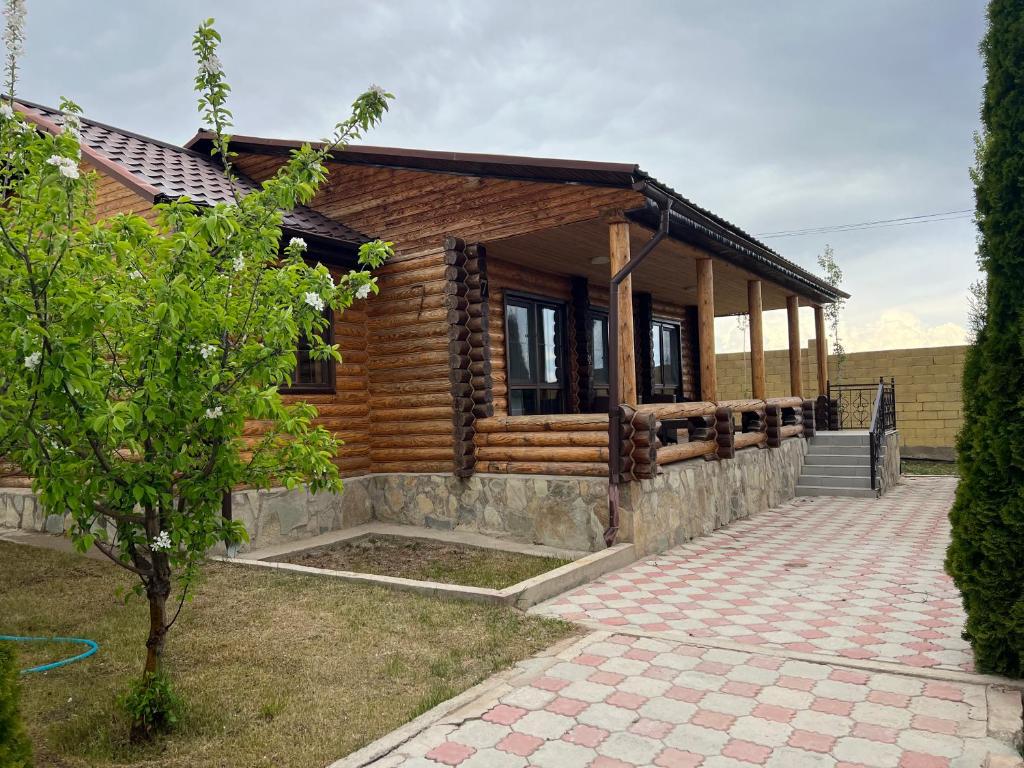 a log home with a porch and a tree at Soho Hutor in Bosteri