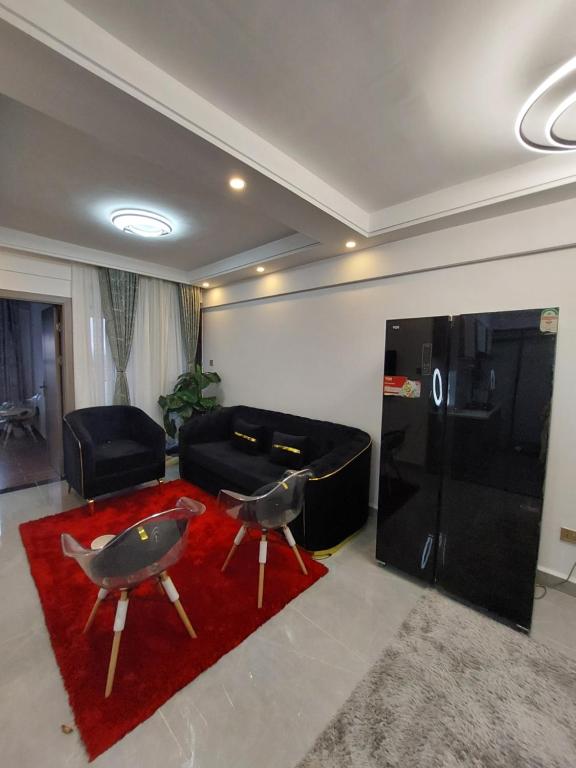 Luxury Apartment Lavington في Mutomo: غرفة معيشة مع أريكة سوداء وسجادة حمراء