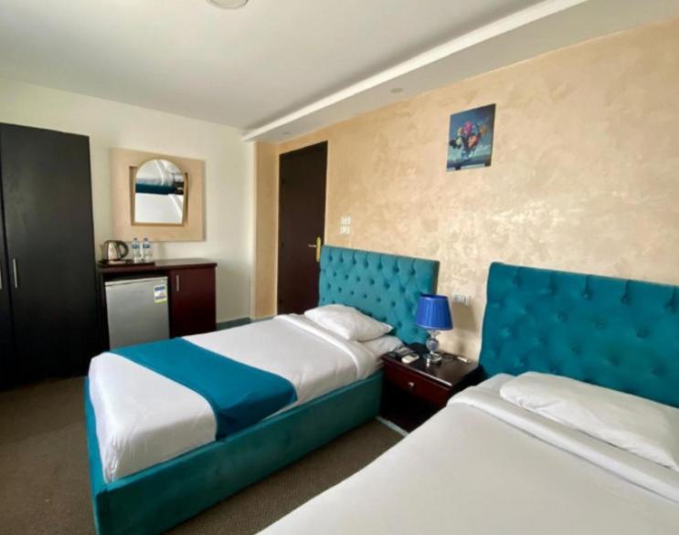 pokój hotelowy z 2 łóżkami z niebieskim zagłówkiem w obiekcie Royal Golden Pyramids Inn w Kairze
