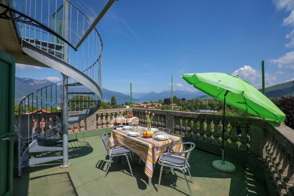 a table and chairs with an umbrella on a balcony at Casa Terra a Cielo in Castelveccana