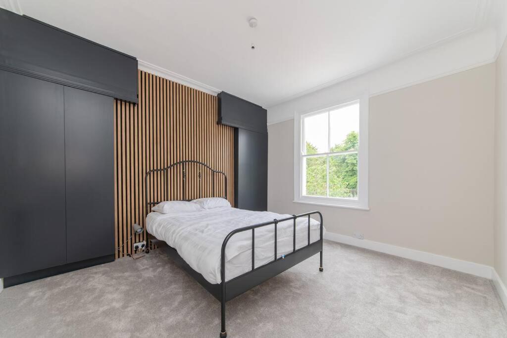 1 dormitorio con cama y ventana en Stylish & Spacious 3-Bed House, Parking and Garden, en Finchley