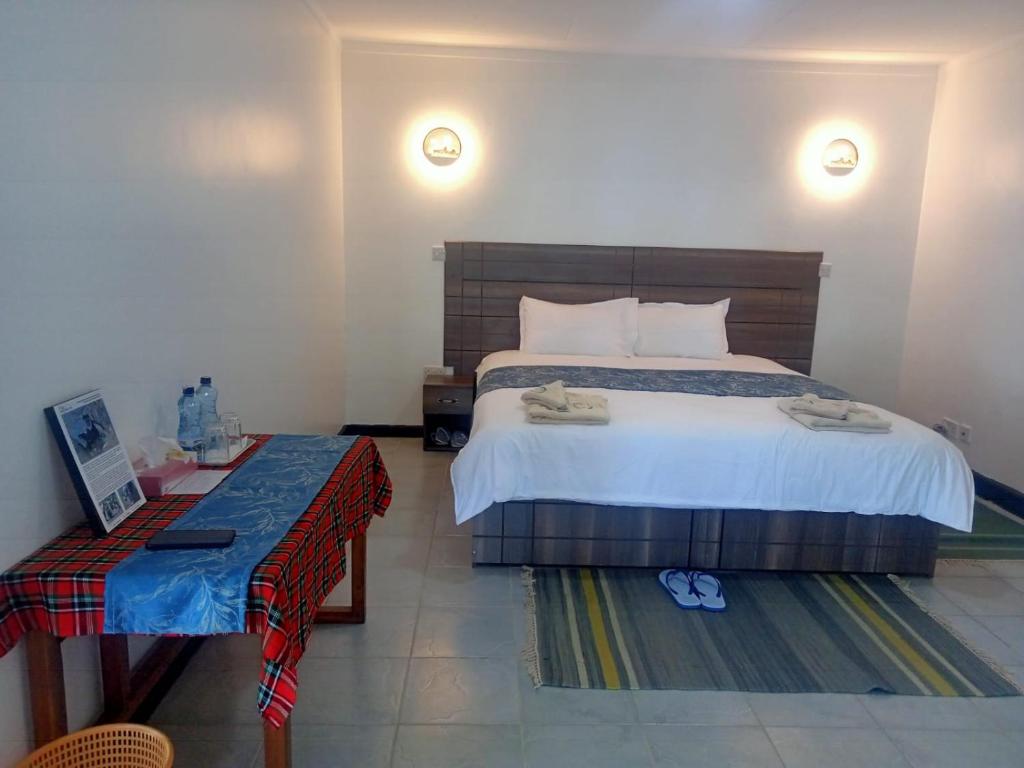 a bedroom with a large bed and a table at Elsamere Lodge Naivasha in Naivasha