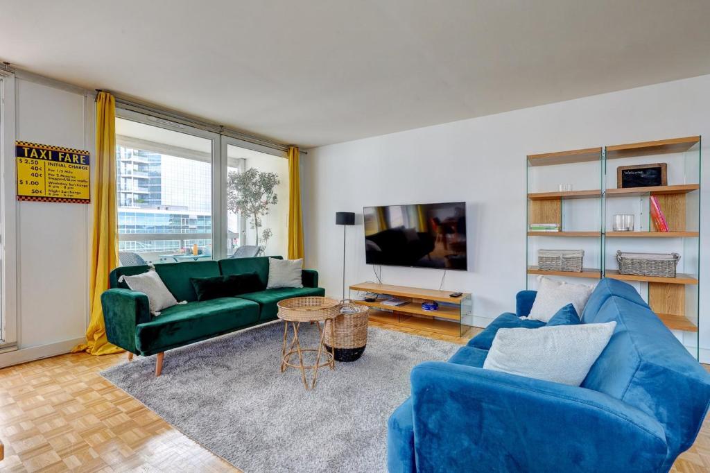 een woonkamer met twee blauwe banken en een tv bij 825 Suite Bacla - Superbe appartement in Courbevoie