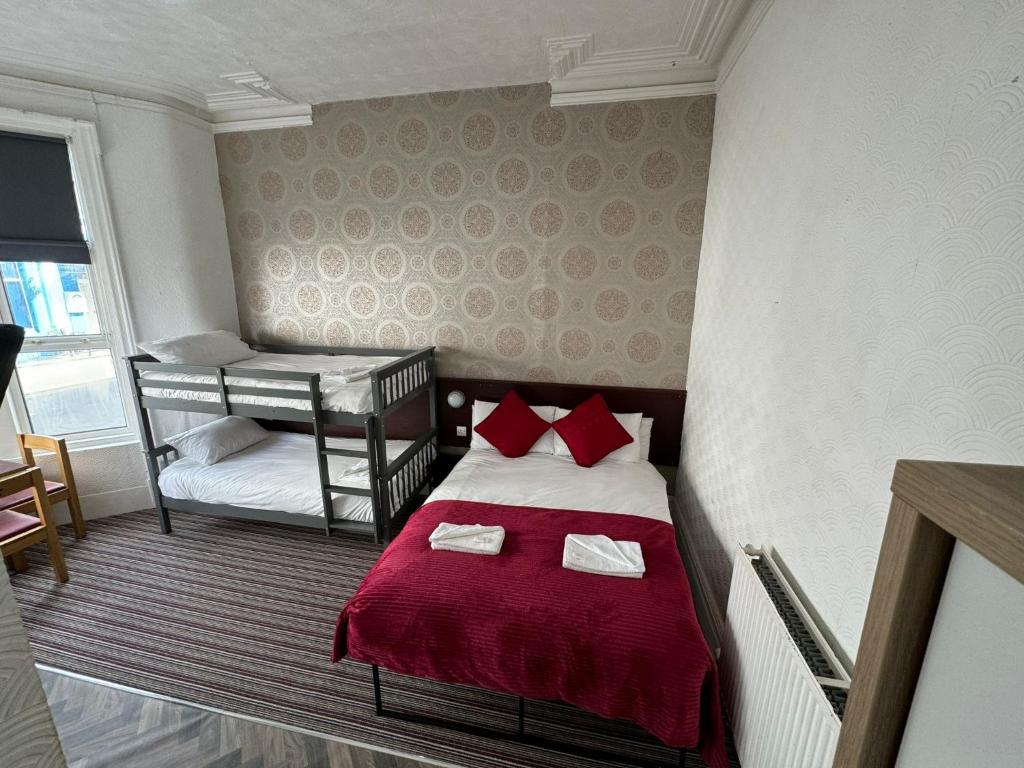 a small bedroom with a bed with red pillows at Wilsons Lodge in Blackpool