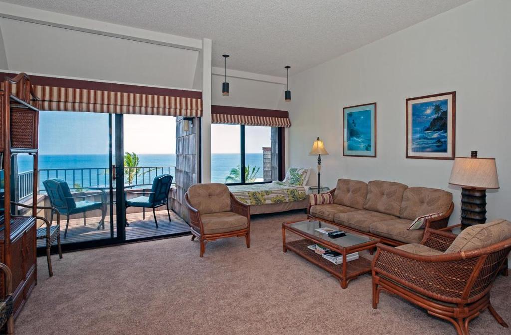 a living room with a couch and chairs and a balcony at Sealodge F9 in Princeville