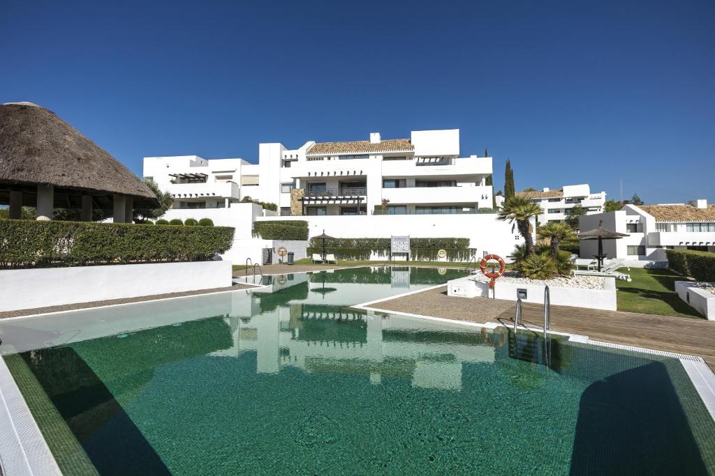 a swimming pool in front of a white building at Tranquil 2-bed apt Alanda Flamingos in Estepona