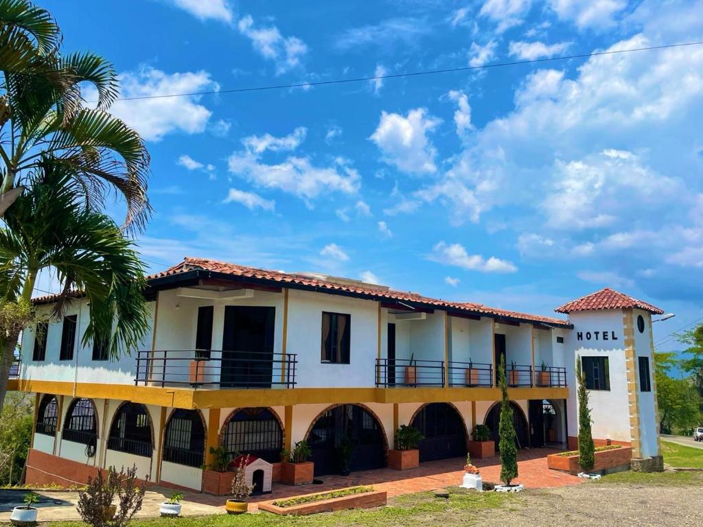 uma casa branca com uma palmeira em frente em Hotel Turístico El Cedral em Socorro