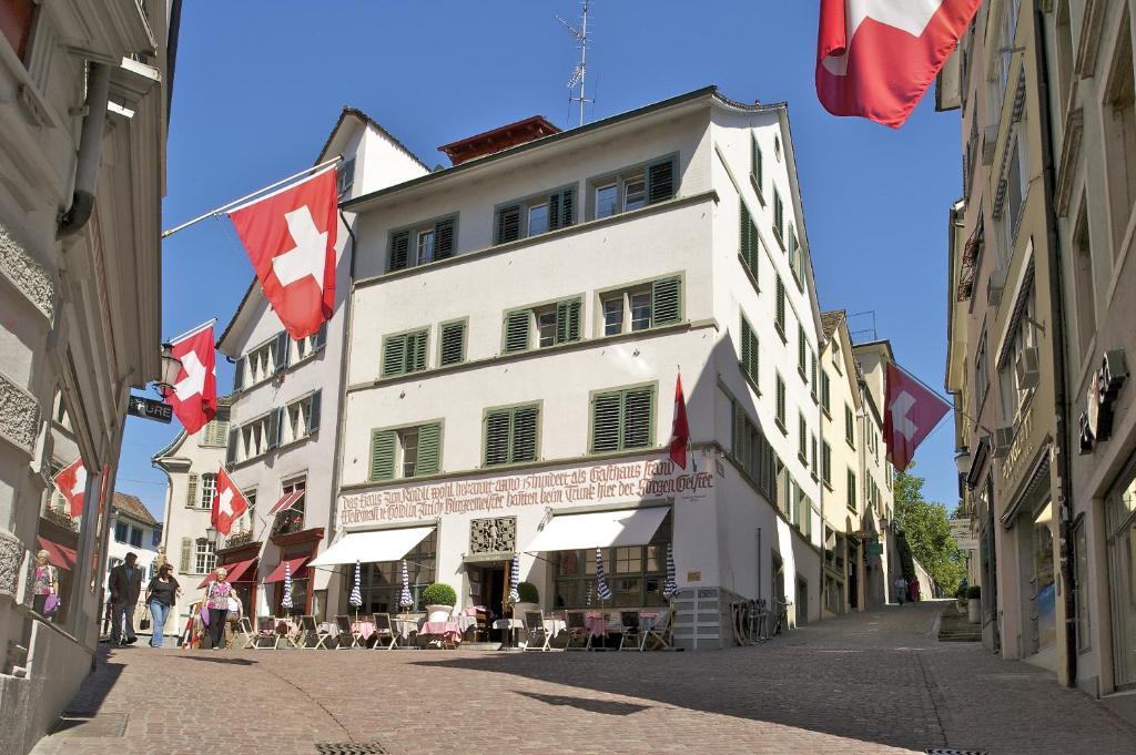 a white building with canadian flags on a street at Hotel Kindli in Zurich