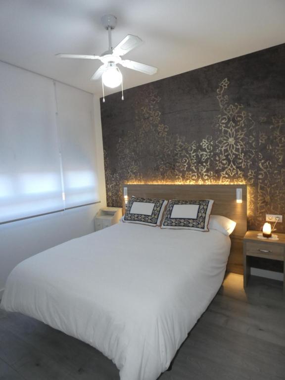 een slaapkamer met een wit bed en een plafondventilator bij Vivienda en centro de Yecla in Yecla