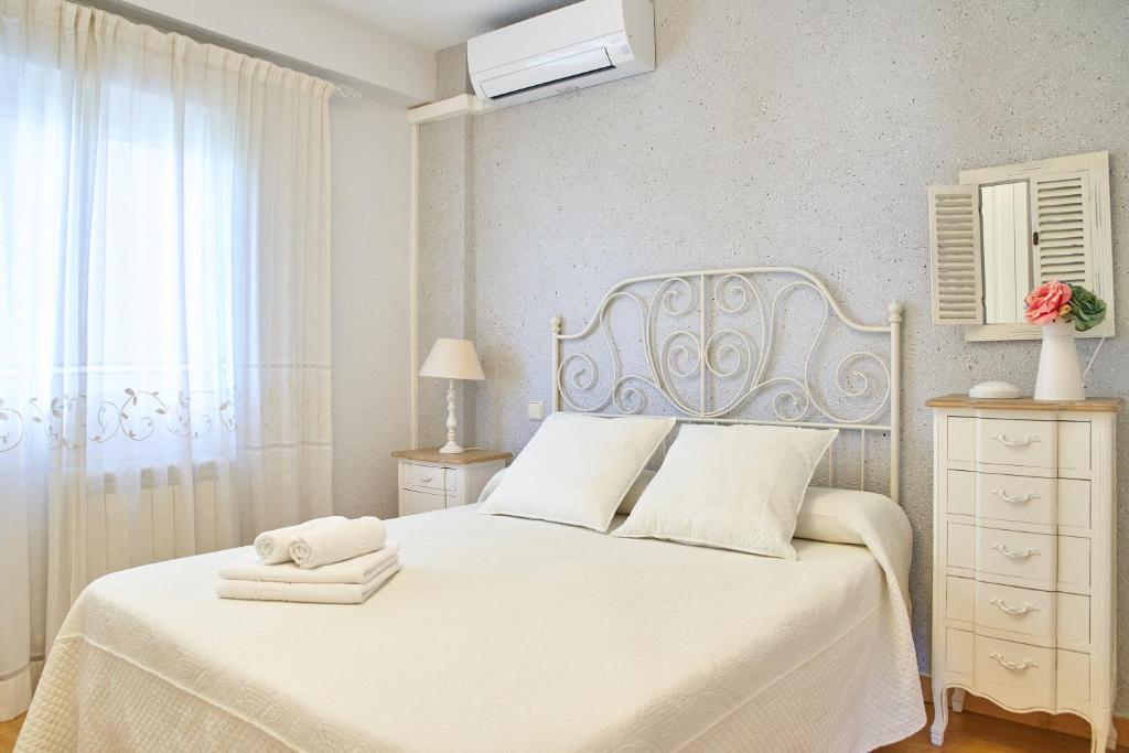 a white bedroom with a white bed and a window at Lux Buenavista in Toledo