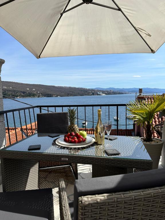 einen Tisch mit einem Obstteller und einem Regenschirm in der Unterkunft Villa Volos apartment Karmen with roof terrace, sea view, free private parking in Opatija