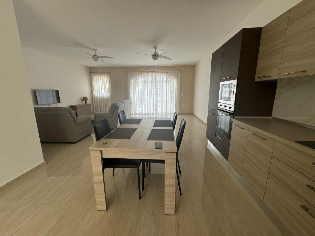 uma cozinha e sala de estar com uma mesa de madeira e cadeiras em Victoria Modern Apartment em Victoria