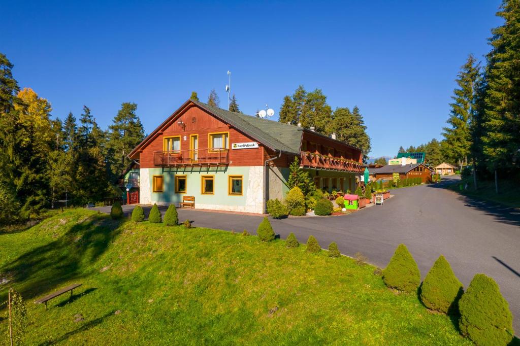 a house on a grassy hill next to a road at Hotel Polovnik in Demanovska Dolina