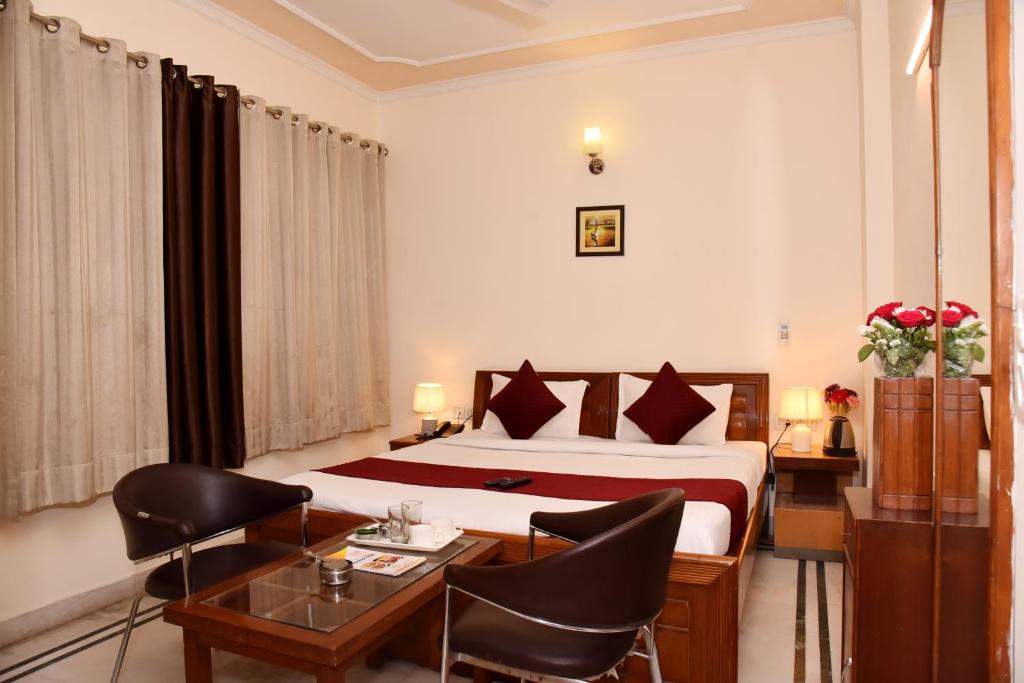 Habitación de hotel con cama, escritorio y sillas en Hotel Gracious en Gurgaon