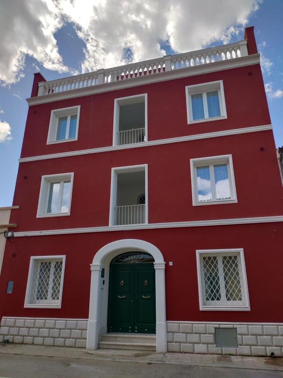 RMaison Luxury Suites Olbia في أولبيا: مبنى احمر مع باب اخضر