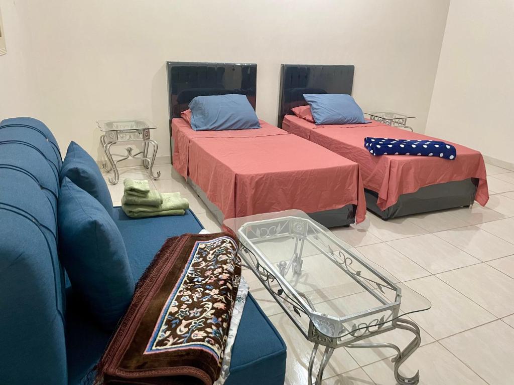 a room with two beds and a blue couch at ستوديو غرفة بحمام in Medina