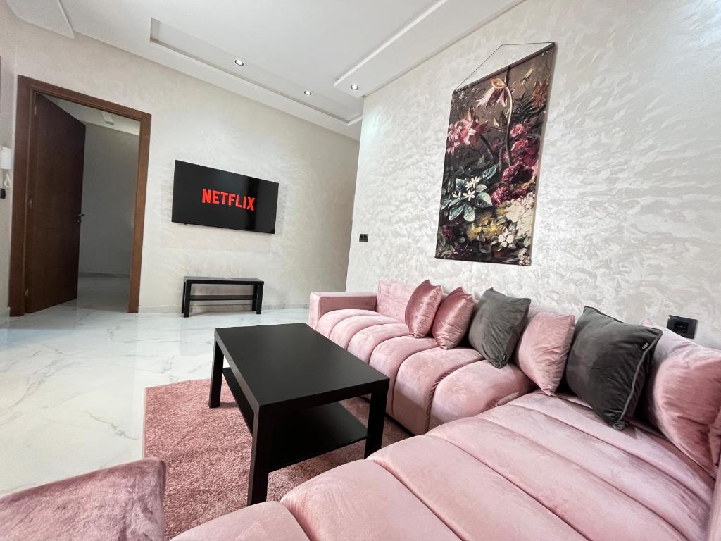 a living room with a pink couch and a table at Modern & Cosy Studio City Center in Kenitra