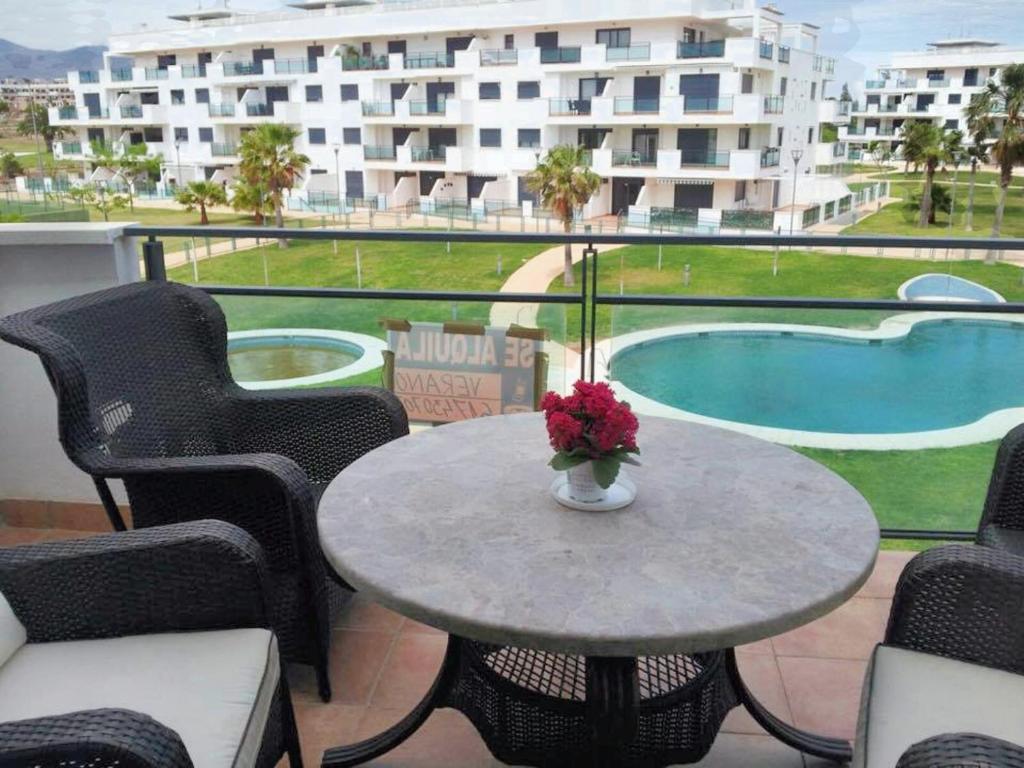 レタマルにある2 bedrooms apartement with shared pool and enclosed garden at Almeria 1 km away from the beachのバルコニーに花瓶付きテーブル